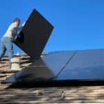 man in white dress shirt and blue denim jeans sitting on white and black solar panel